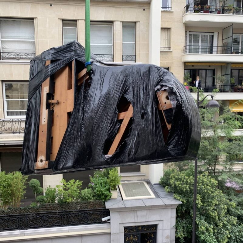 Photo d'un piano à queue suspendu à un balcon lors d'un débarras d'appartement.