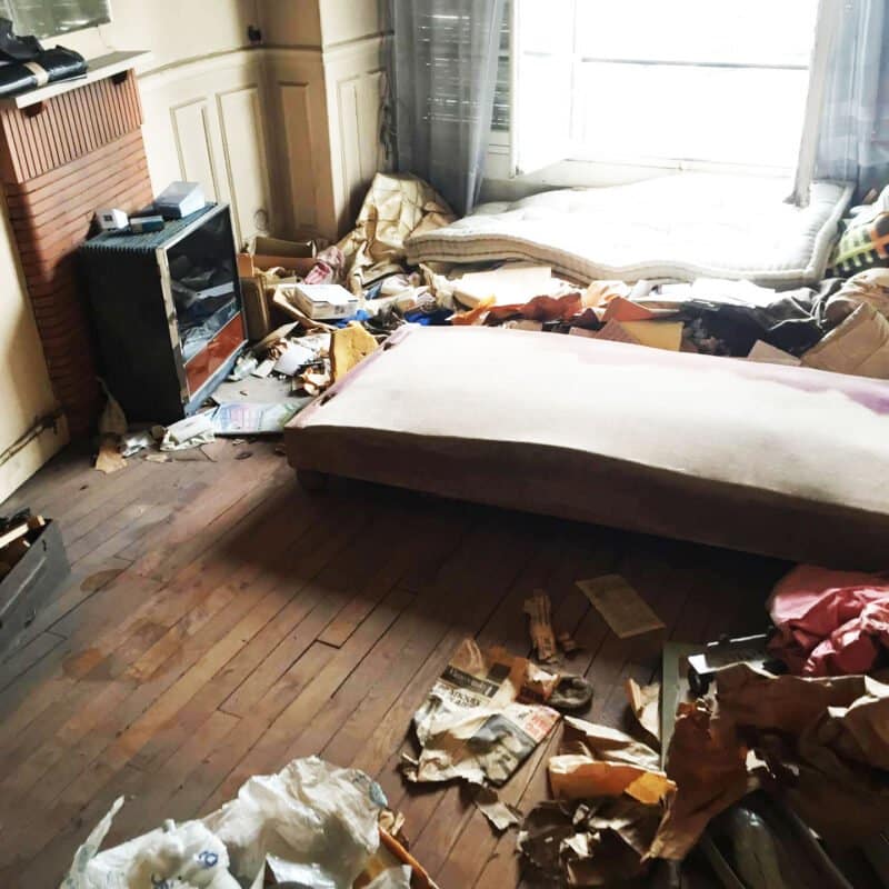 Photo de la chambre d'une maison en désordre. Jonchée de détritus au sol.