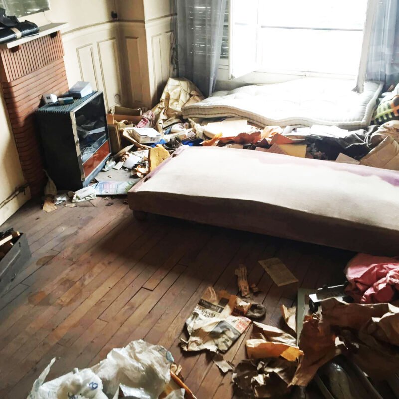 Photo de la chambre d'une maison en désordre. Jonchée de détritus au sol.